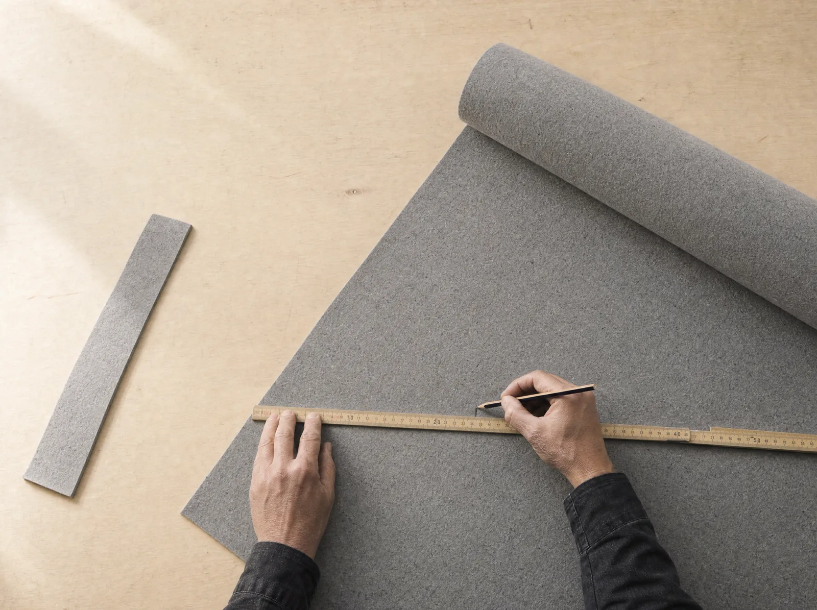 Ein Materialbogen wird mit Massstab und Bleistift ausgemessen.